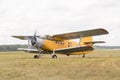 Old yellow biplane with switched on motor stay on grass field Royalty Free Stock Photo