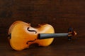Old yellow broken violin without strings lies on a side on brown antique wood background Royalty Free Stock Photo