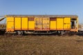 Old yellow cargo train wagon, grungy and weathered on the abandoned train tracks