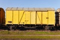 Old yellow cargo train wagon, grungy and weathered on the abandoned train tracks