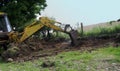 Old Yellow Digger digging stones and rocks on farm