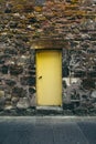 Old yellow door in the stone wall, Scotland. Royalty Free Stock Photo