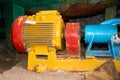 Old yellow electric motor with a blue pump connected.