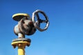 Old yellow gas pipe with valve on blue sky background Royalty Free Stock Photo