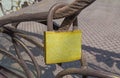 Old yellow glittering padlock with rust hanging on metal fence
