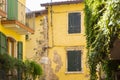 Old yellow house facade, green window shutters and balcony