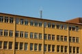 Old yellow industrial building. Communications antennae on the roof.. Royalty Free Stock Photo