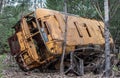 Old yellow rust bus lays abandoned in Chernobyl Exclusion Zone forest