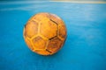 Old yellow soccer ball on the blue football field Royalty Free Stock Photo