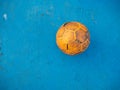 Old yellow soccer ball on the blue football field Royalty Free Stock Photo