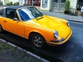 Old yellow sports car with a black roof, parked on a main street. Concept of power, power and wealth Royalty Free Stock Photo