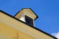 old yellow stucco roof dormer with small wood window. sloped clay tile roof . metal flashing trimmed edges