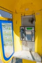 An old yellow telephone booth stands in the street, forgotten communication technologies unused by man. Royalty Free Stock Photo