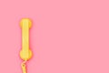 An old yellow telephone receiver on a pink background Royalty Free Stock Photo