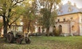 An old yellow tractor standing on a farm with a background of autumn leaves