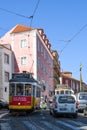 Old yellow tram acrossing pink building in alfama downtown Royalty Free Stock Photo
