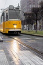 Old yellow tram on gray city street. Urban vintage train. Transport and travel concept. City tram in Budapest. Royalty Free Stock Photo