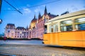 Old yellow tram speeds up along city streets at night. The historical center of the capital of Hungary