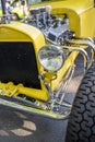 Old yellow vintage retro car with open chrome engine and chassis of a provincial town standing at an exhibition on the street Royalty Free Stock Photo