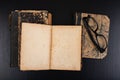 Old yellowed book and black glasses. Forgotten publications on the dark table Royalty Free Stock Photo