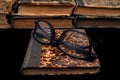 Old yellowed book and black glasses. Forgotten publications on the dark table Royalty Free Stock Photo