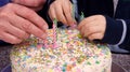 Old & young hands put candles on a cake Royalty Free Stock Photo