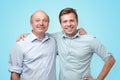 Old and young men standing together on blue studio wall. Royalty Free Stock Photo