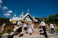 Old and young village people walking past the wooden Orthodox church