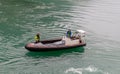 Olden, Norway - July 18, 2023: Alertness on the fjord. Two workers in safety gear navigate a small boat across the calm