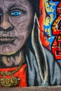 Older, aged American Indian with necklace and feather colourful graffiti mural on the wall