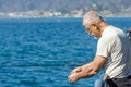 Older aged man fishing off a pier, Santa Monica