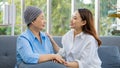 Older Asian woman patient covered the head with clothes effect from chemo treatment in cancer cure process hold hands of daughter