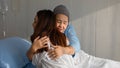 Older Asian woman patient covered the head with clothes effect from chemo treatment in cancer cure process hugging her daughter