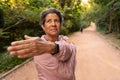 Older brazilian woman with pink jacket stretching arms before exercise. Outdoors in sunny day. Fit, freedom, joy, vitality
