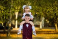 Older brother and younger sister walk in autumn park in school uniform