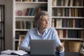 Older businesswoman sit at workplace distracted from work staring aside Royalty Free Stock Photo