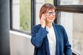 Older businesswoman talking phone indoors Royalty Free Stock Photo