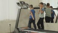 The older child is training the younger to walk on the treadmill