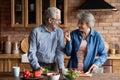 Older couple cooking together healthy food in modern kitchen