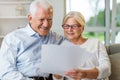 Older couple reading papers together on sofa