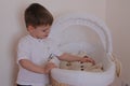 Older brother puts little sister to sleep in a white cot