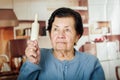 Older cute hispanic woman in blue sweater holding up a rolling pin