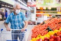 Older european man wearing mask and gloves with covid protection shoping in supermarket