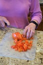 Elderly woman cuts tomatoes on counter Royalty Free Stock Photo