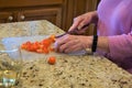 Elderly woman cuts tomatoes on counter Royalty Free Stock Photo