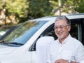 An older gentleman stood in front of his car looking smart.