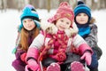 Older girl and boy push sled in which younger girl sits