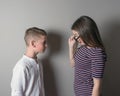 Older girl scolding younger boy on gray background