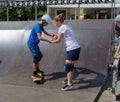 Older girl teach younger boy how to ride a skateboard. Skateboard lesson