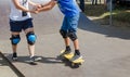 Older girl teach younger boy how to ride a skateboard. Skateboard lesson